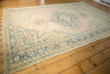 Distressed vintage Oushak carpet corner, with faded blue geometric border and seafoam green accents.