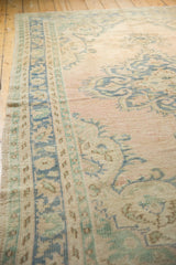 Distressed pile of the vintage Oushak rug with faded pink, blue, and mint patterns.