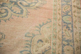 Close-up of Vintage Distressed Oushak rug showing pale pink field and denim blue motifs.