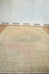 Pale dusty pink, seafoam green distressed Oushak rug with even pile wear.