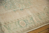 Seafoam green and antique ivory patterns on the distressed vintage Oushak rug's low pile.