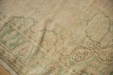 Distressed Oushak rug with even wear showing seafoam green and beige patterns.