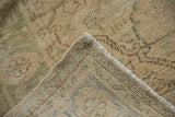 Close-up of distressed Oushak rug corner, showing worn beige pile and hand-knotted foundation.