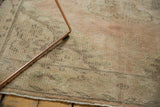 Distressed vintage Oushak rug pile, showing mostly even wear, pale blush, and seafoam green vinery.