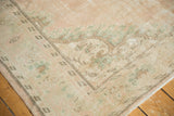 Corner of distressed vintage Oushak rug, showing pale blush pile and visible foundation.