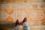 Distressed tangerine orange Oushak runner with faded ivory geometric floral motifs.