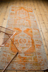 Distressed tangerine orange and ivory geometric floral motifs on a vintage Oushak rug runner.