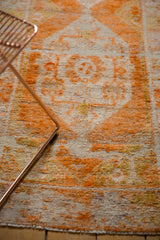 Distressed Oushak runner with tangerine geometric floral motif and wear to foundation.