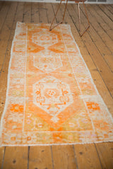 Vintage Oushak runner with worn tangerine orange geometric floral motif and fringe.