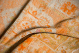 Distressed tangerine orange and ivory pile with faded geometric patterns on a vintage Oushak rug.