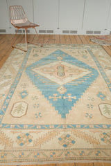 Distressed Oushak carpet with fringe, geometric border, and abrashed ivory and turquoise field.