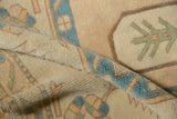 Curled distressed Oushak rug pile showing abrashed ivory ground and stylized turquoise motif.