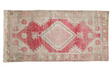 Distressed vintage Oushak runner, dusty raspberry diamond medallion, ivory field, worn texture.