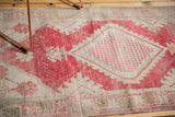 Distressed vintage Oushak rug texture, dusty raspberry lattice motif, and exposed foundation.