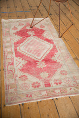 Faded dusty raspberry and beige geometric floral border on distressed Oushak runner corner.