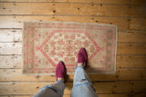 Vintage distressed Oushak rug with even wear, dusty rose medallion, and beige ground.