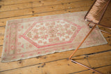 Distressed vintage Oushak rug with dusty rose pinwheel florals, narrow border, and even wear.