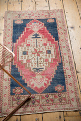 Distressed Oushak rug detail: stepped medallion in blush, deep navy field, and ivory border.