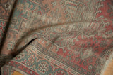 Distressed texture of the Anatolian rug revealing faded dusty rose and oxidized copper green patterns.