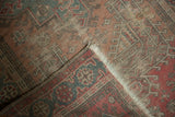 Folded vintage Anatolian rug revealing distressed dusty rose pattern, fringe, and woven foundation.