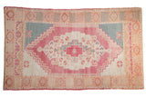 Vintage hand-knotted Oushak rug with faded raspberry medallion, ivory field, and ocean teal spandrels.
