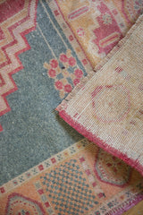 Corner of distressed Oushak rug with worn pile, visible knot heads, and hand-knotted back.