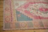 Distressed Oushak rug corner, faded pale tangerine and teal geometric borders, even wear.