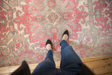 Distressed Oushak carpet in pale dusty cherry and slate blue, showcasing textured wear with feet.