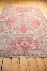 Distressed Oushak rug detail showing curvilinear motifs in pale dusty cherry and soft slate blue.