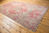 Decorative distressed Oushak rug pile with pale cherry, ivory, and slate blue motifs.