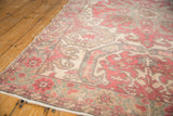 Distressed Oushak rug corner with faded cherry flowers, geometric inner border, and fringe.