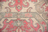 Distressed Oushak rug detail with faded cherry, ivory, and slate blue curvilinear motifs.