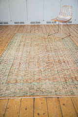Distressed vintage Oushak rug showing worn foundation, short fringe, and soft apricot, mint.
