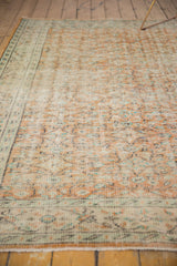 Distressed Oushak texture, pale apricot floral vinery, mint green border, visible foundation.