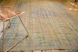 Angled view of distressed vintage Oushak carpet with faded apricot and royal blue vinery.