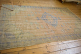 Distressed vintage Oushak rug close-up: faded royal blue border, apricot field with vinery.