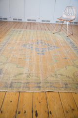 Secured end of the distressed vintage Oushak carpet, showing even wear and faint foundation.