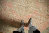Vintage Distressed Oushak carpet's faded dusty rose, seafoam green, and visible foundation wear.