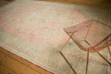 Distressed Oushak carpet with faded pink, seafoam green floral vinery, foundation showing.