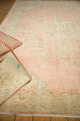 Faded pink and seafoam green Oushak rug with distressed texture, floral vinery.