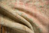 Worn texture of a vintage distressed Oushak rug with soft pink, seafoam green, and ivory colors.