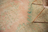 Distressed vintage Oushak rug pile with faded pink, seafoam floral motifs and visible foundation.