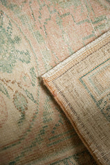 Distressed vintage Oushak rug pile with faded blush and seafoam, revealing reverse weave.