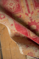 Textured low pile of distressed Oushak rug with blush and ivory motifs.