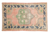 Vintage distressed Oushak rug in faded pink with green medallion and navy border, 2'9