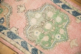 Distressed pink, green scalloped medallion, and navy border details on a vintage Oushak rug.