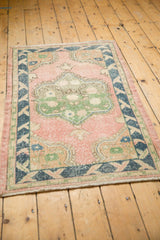 Faded pink pile and worn texture of a vintage Oushak rug corner with geometric border.