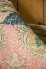 Distressed Oushak rug's pile showing wear, faint foundation, pink, navy, green patterns.