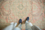 Distressed texture of vintage Oushak carpet featuring blush, ivory, and charcoal vinery.