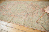 Vintage Distressed Oushak rug showing worn blush, pale seafoam, and charcoal vinery motifs.